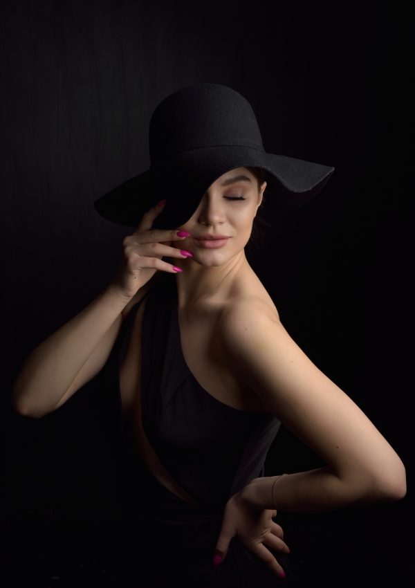 Beautiful woman in hat. Retro fashion. Dark Background.